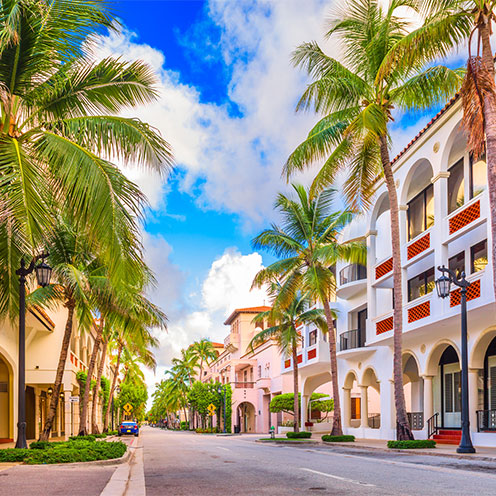 Palm tree-lined community in Florida with mediterranean-style apartments and store fronts Palm tree-lined community in Florida with mediterranean-style apartments and store fronts